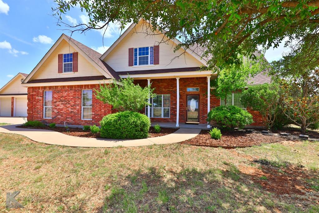 a front view of a house with a yard and potted plants