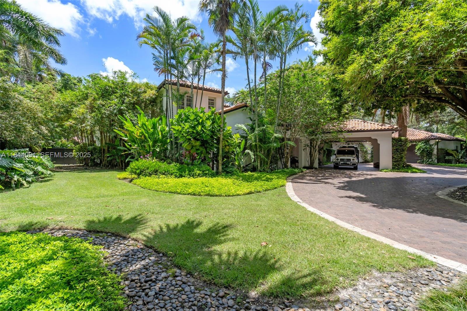 7320 Southwest 79th Court Miami, FL 33143 - Photo 18 of 89 a view of a white house with a big yard and potted plants and large trees