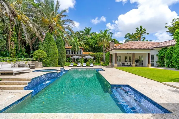 a living room with patio furniture and a floor to ceiling window next to a yard