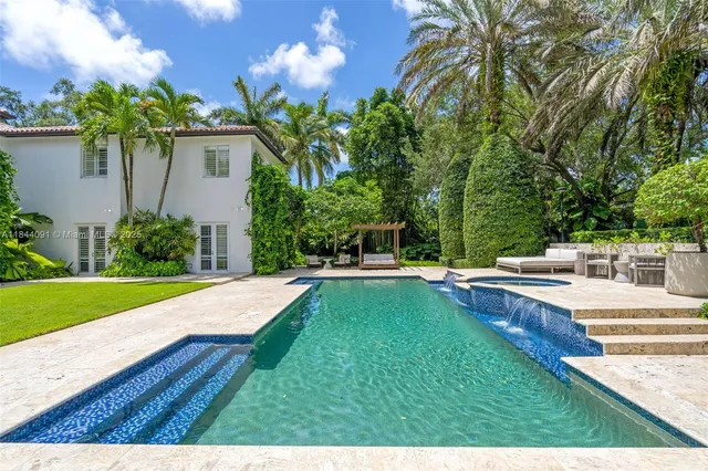 a living room with patio furniture and a floor to ceiling window next to a yard