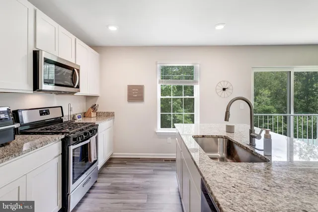a kitchen with stainless steel appliances granite countertop a stove a sink and a microwave
