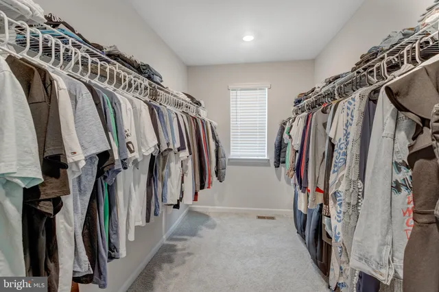 a view of walk in closet with clothes and shoes