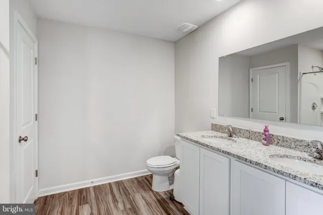 a bathroom with a granite countertop sink a toilet and a mirror