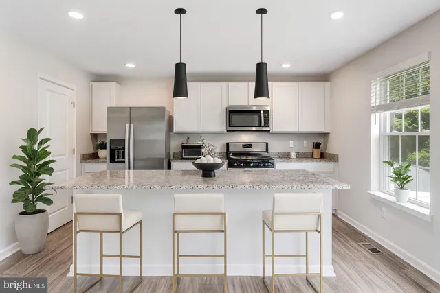 a kitchen with stainless steel appliances kitchen island granite countertop a stove a refrigerator a sink a dining table and chairs with wooden floor