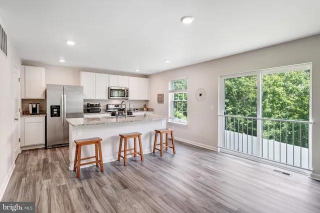 a kitchen with stainless steel appliances granite countertop a refrigerator a stove top oven a sink and cabinets with wooden floor