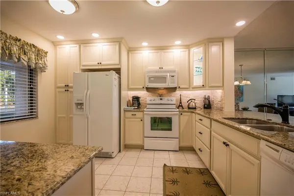 a kitchen with white cabinets appliances and a sink