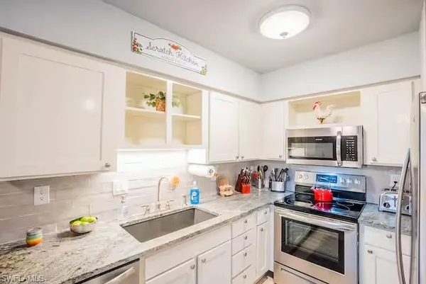 a kitchen with stainless steel appliances granite countertop a sink a stove and cabinets