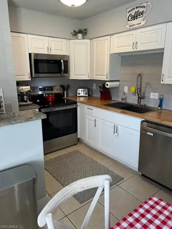 a kitchen with stainless steel appliances a sink a stove a microwave a refrigerator a sink and cabinets