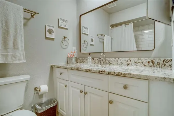 a bathroom with a granite countertop sink a toilet and a mirror