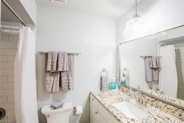 a bathroom with a granite countertop sink a toilet and shower