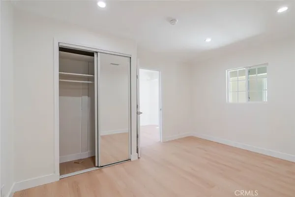 an empty room with wooden floor and closet area