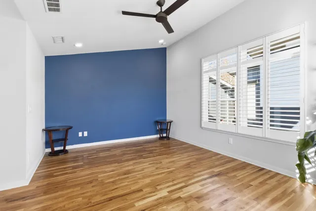 a view of an empty room with a window and wooden floor