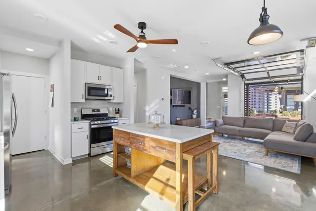 a large white kitchen with a refrigerator a stove a sink a dining table and chairs with wooden floor