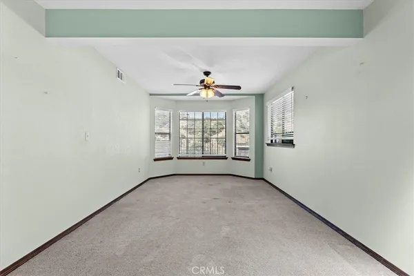 an empty room with windows and ceiling fan