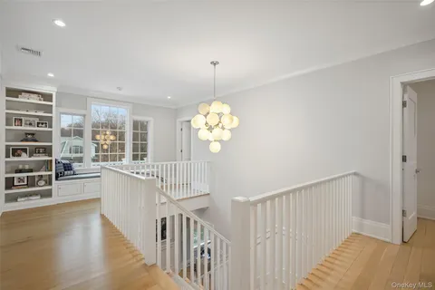 a view of a hallway with wooden floor and chandelier