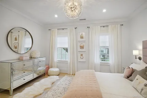 a bedroom with a bed a mirror and a large window