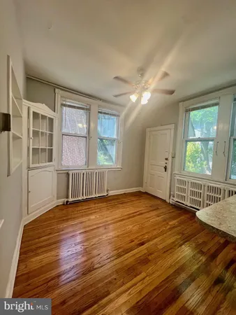a view of an empty room with a window and wooden floor