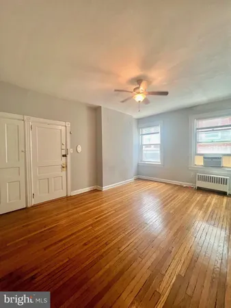 a view of an empty room with window and wooden floor