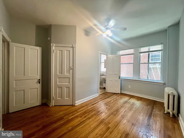 a view of empty room with wooden floor and fan