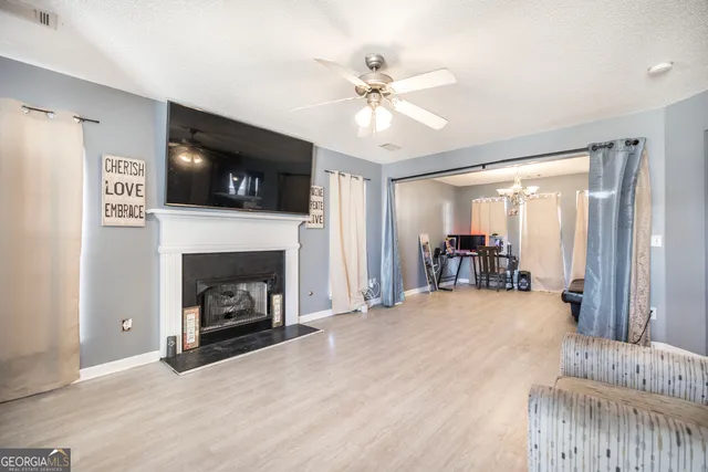 a view of a livingroom with a fireplace a ceiling fan and windows