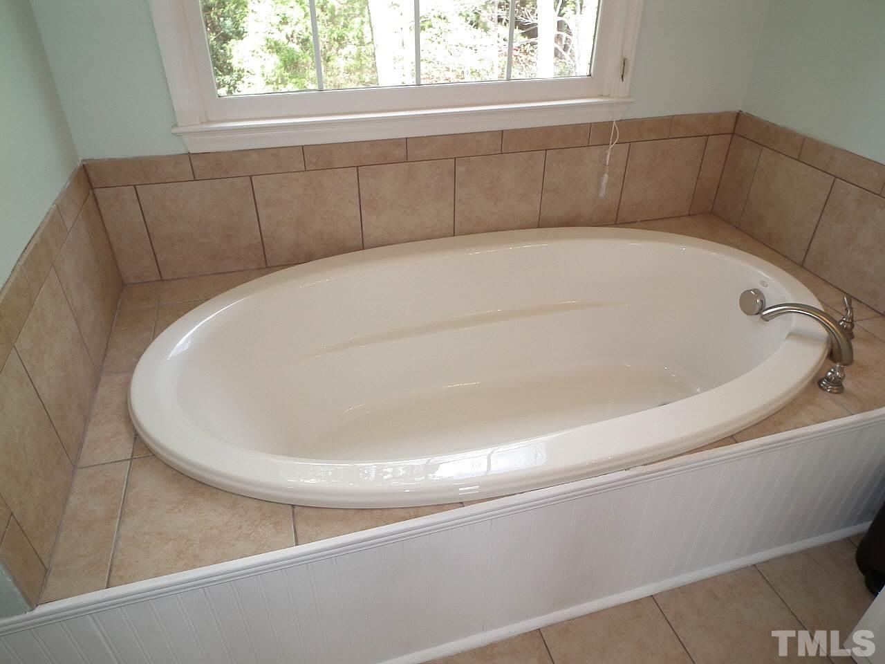 7016 Edgeview Court Raleigh, NC 27613 - Photo 14 of 25 a white bath tub sitting in a bathroom