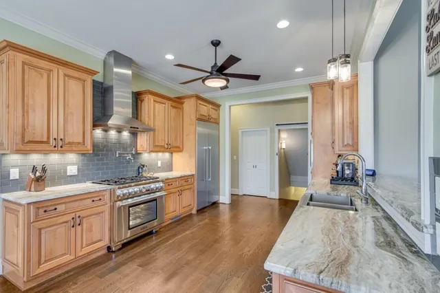 a kitchen with stainless steel appliances a stove a sink and white cabinets with wooden floor