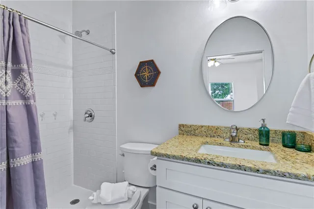 a bathroom with a granite countertop sink mirror vanity and toilet