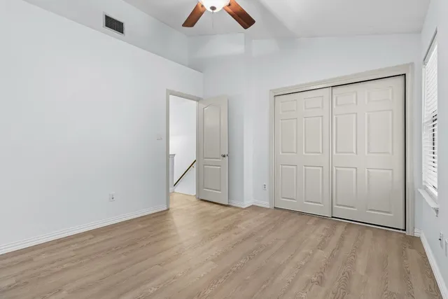 an empty room with ceiling fan and windows
