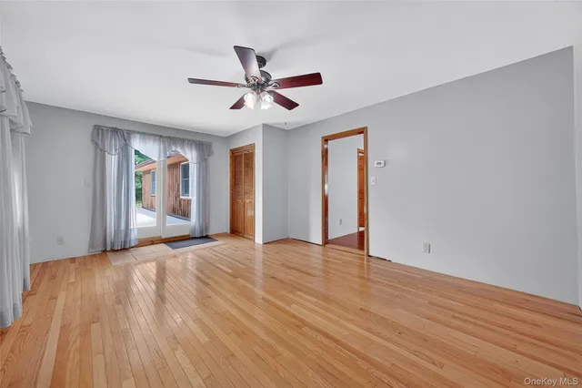 a view of an empty room with window and wooden floor