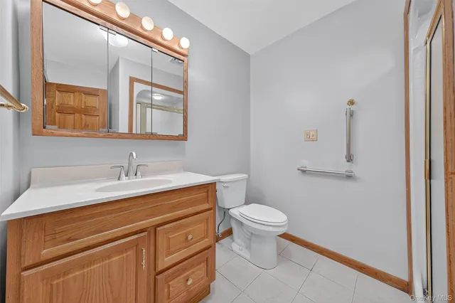 a bathroom with a granite countertop sink toilet and mirror