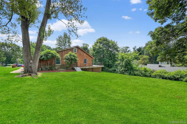 a yellow and red house with a big yard and large trees