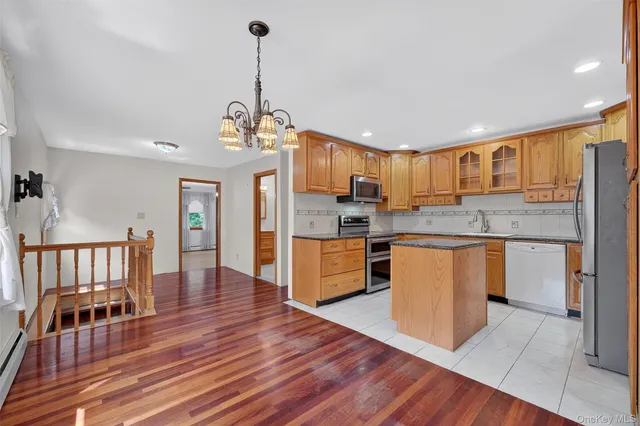 a kitchen with stainless steel appliances granite countertop a stove a sink dishwasher a refrigerator and a dining table with wooden floor