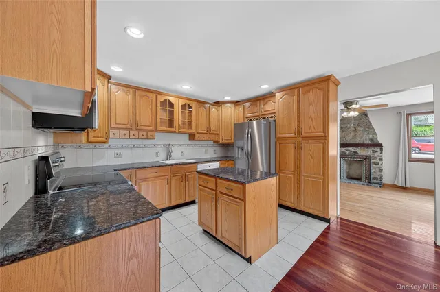 a kitchen with stainless steel appliances granite countertop a refrigerator a stove and a sink with wooden floors