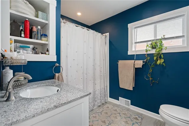 a bathroom with a granite countertop sink a toilet and a shower