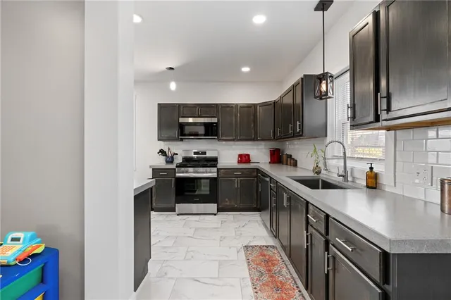 a kitchen with stainless steel appliances a sink dishwasher a stove top oven a refrigerator with wooden cabinets and floor