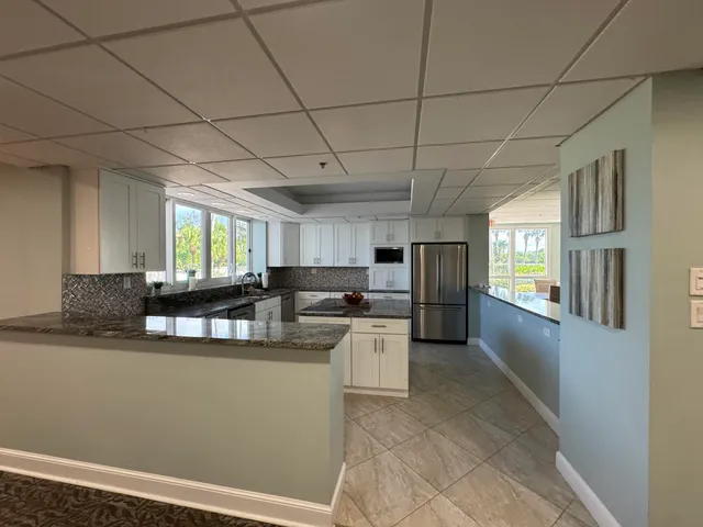 a kitchen with stainless steel appliances kitchen island granite countertop a refrigerator a sink dishwasher a stove and white cabinets