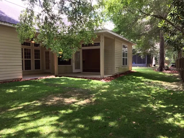 a backyard of a house with plants and large tree
