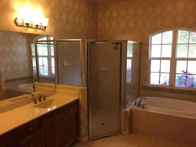 a bathroom with a tub sink shower and mirror
