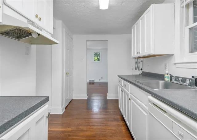 a kitchen with granite countertop a sink and dishwasher a stove top oven with wooden floor