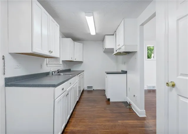 a kitchen with granite countertop a sink a stove and cabinets