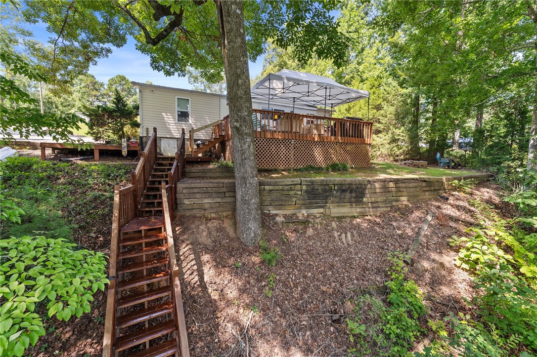 30 Mobleys Bluff Road Abbeville, SC 29620 - Photo 1 of 35 Wooden steps descend along a sloped hillside beneath a spacious elevated deck and canopy.