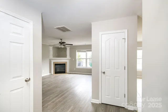 an empty room with wooden floor fireplace and windows