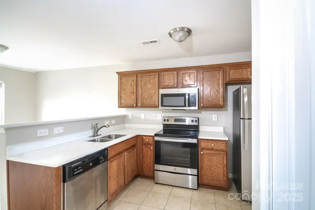 a kitchen with stainless steel appliances a sink stove refrigerator and microwave