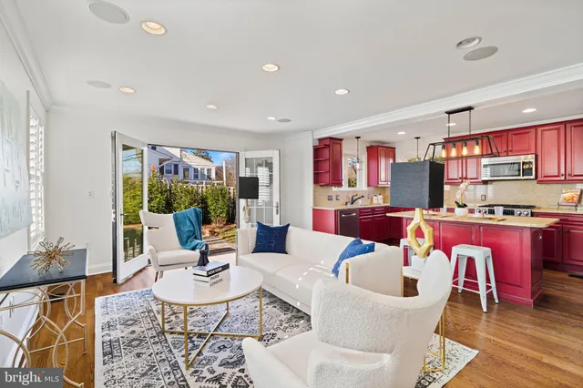 a living room with stainless steel appliances furniture a rug and a kitchen view