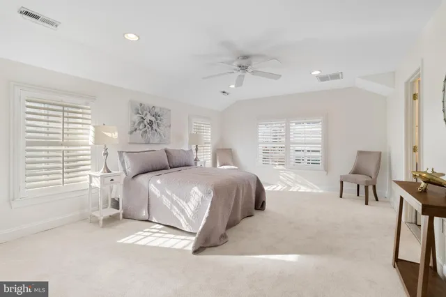 a spacious bedroom with a bed a chair and a large window
