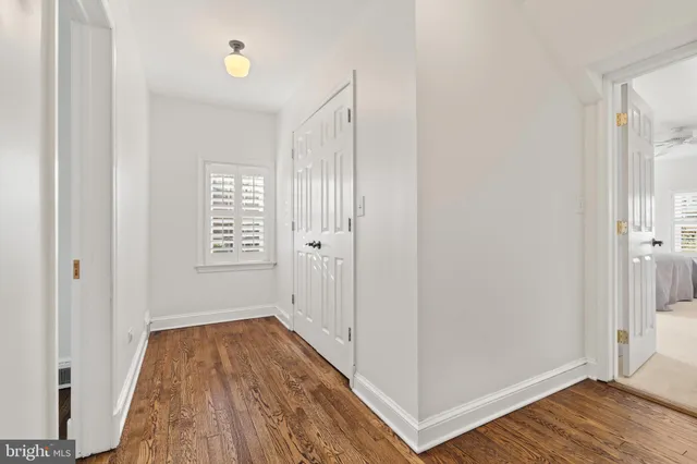 a view of a hallway with wooden floor and a bathroom