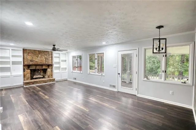 an empty room with windows fireplace and wooden floor