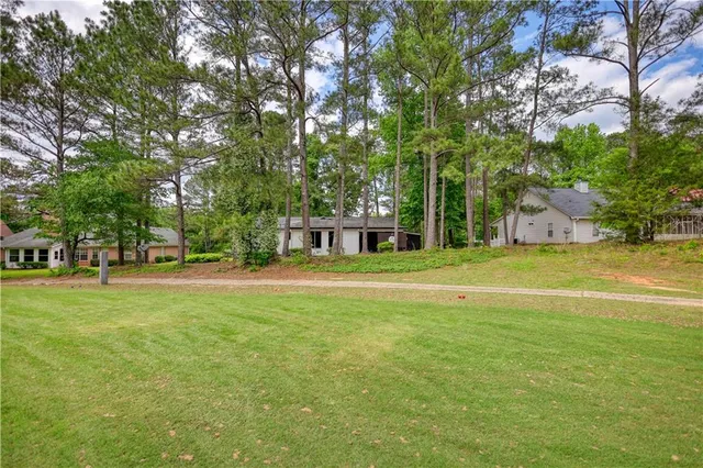 a view of a house with a big yard and large trees