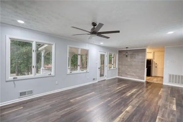 a view of an empty room with a window and wooden floor