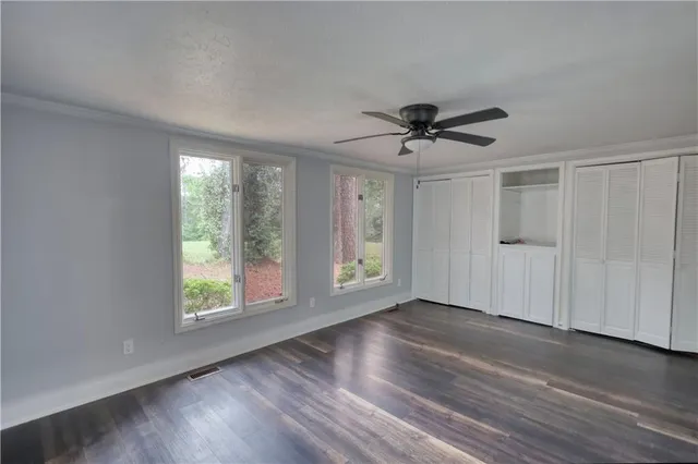 an empty room with wooden floor and windows